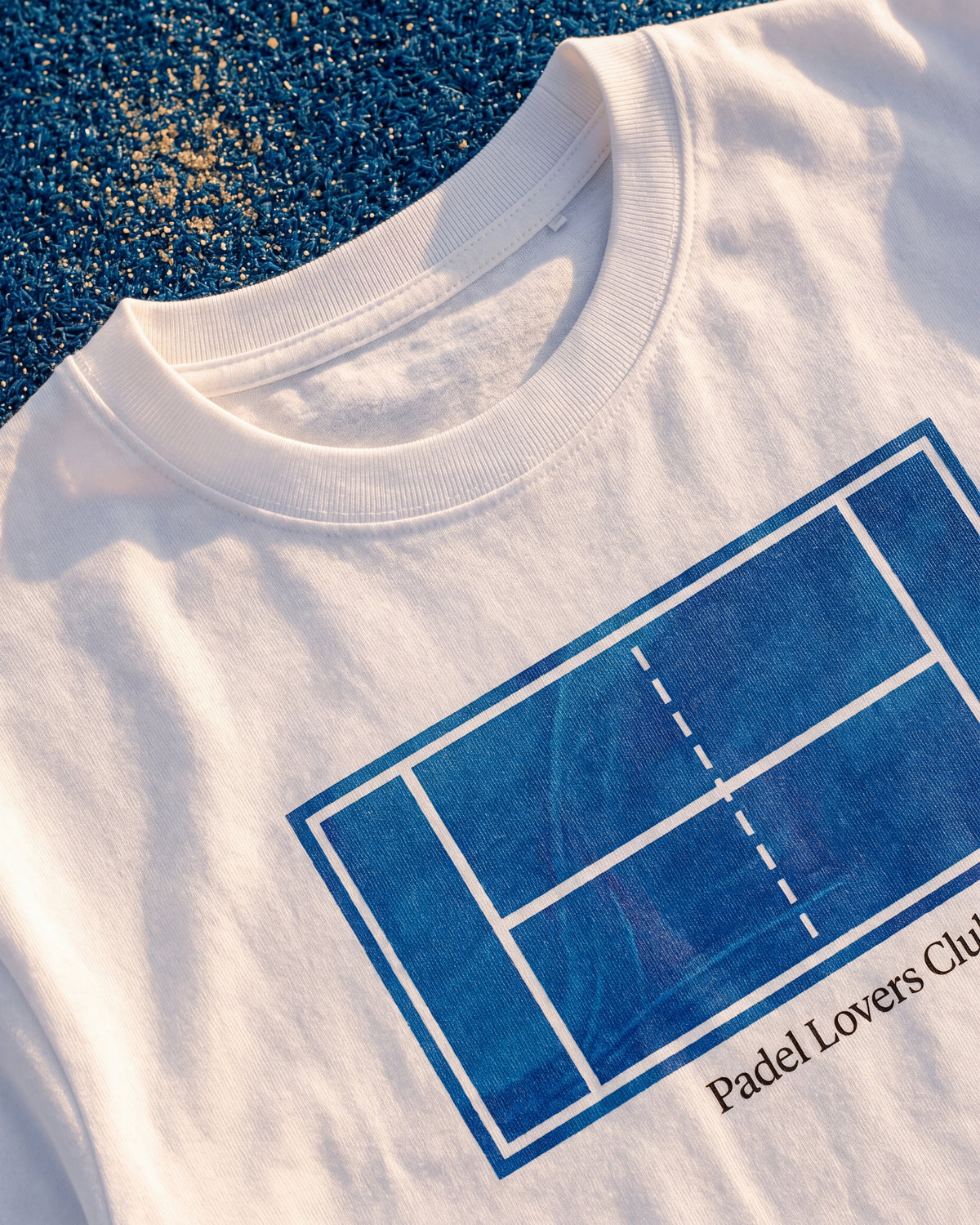 T-shirt padel Art blanc, porté sur un terrain de padel – Padel Lovers Club