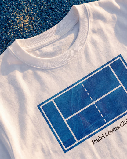 T-shirt padel Art blanc, porté sur un terrain de padel – Padel Lovers Club